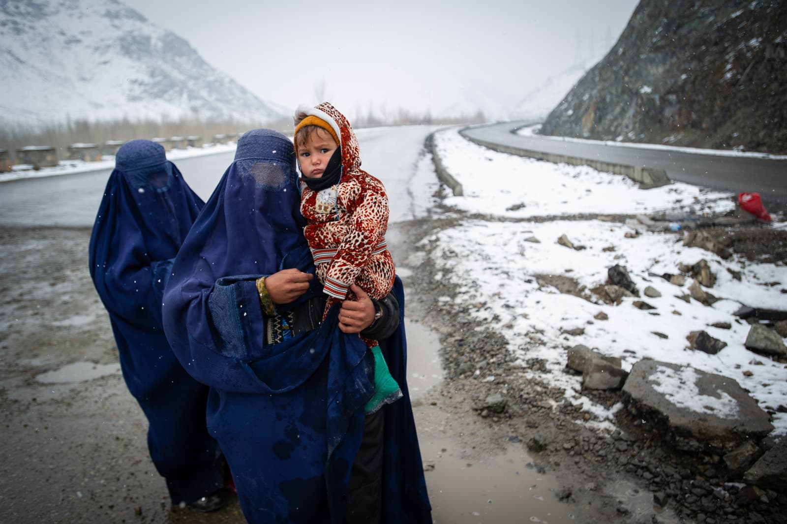 PUL-E ALAM, AFGHANISTAN -- JANUARY 17: Afghan women beg in the snow, with a child, on the Kabul road south to Pul-e Alam, Afghanistan, on January 17, 2022.(Photo by Scott Peterson/Getty Images)